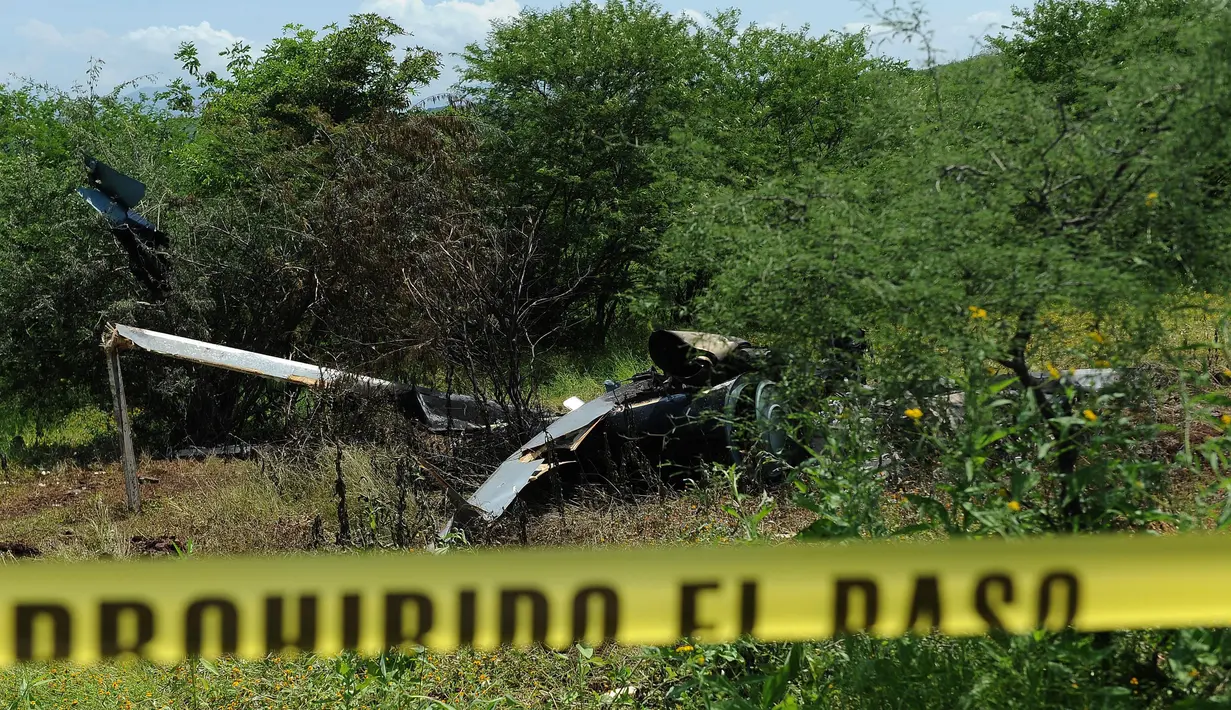 Garis polisi dipasang di dekat jatuhnya helikopter polisi yang diduga ditembak sekelompok geng kartel narkoba di Michoacan, Meksiko, Rabu (7/9). Helikopter itu sedang mendukung operasi penangkapan terhadap para pemimpin geng kriminal. (PEDRO PARDO/AFP)