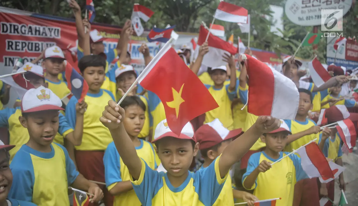 Siswa-siswi SD membawa bendera negara peserta Asian Games 2018 untuk menyambut Kirab Obor di kawasan Jati Padang, Pasar Minggu, Rabu (15/8). Mereka memenuhi jalanan untuk menyaksikan langsung Pawai Obor Asian Games 2018. (Liputan6.com/Faizal Fanani)