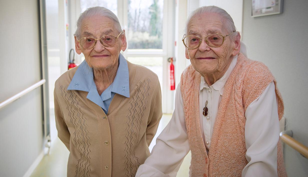 Simone Thiot (kiri) dan Paulette Olivier berjalan saat berada di Ephad "Les Bois Blancs", Prancis (13/2). Paulette dan Simone perempuan berusia 104 tahun ini diyakini sebagai wanita kembar tertua di dunia. (AFP PHOTO/GUILLAUME souvent)