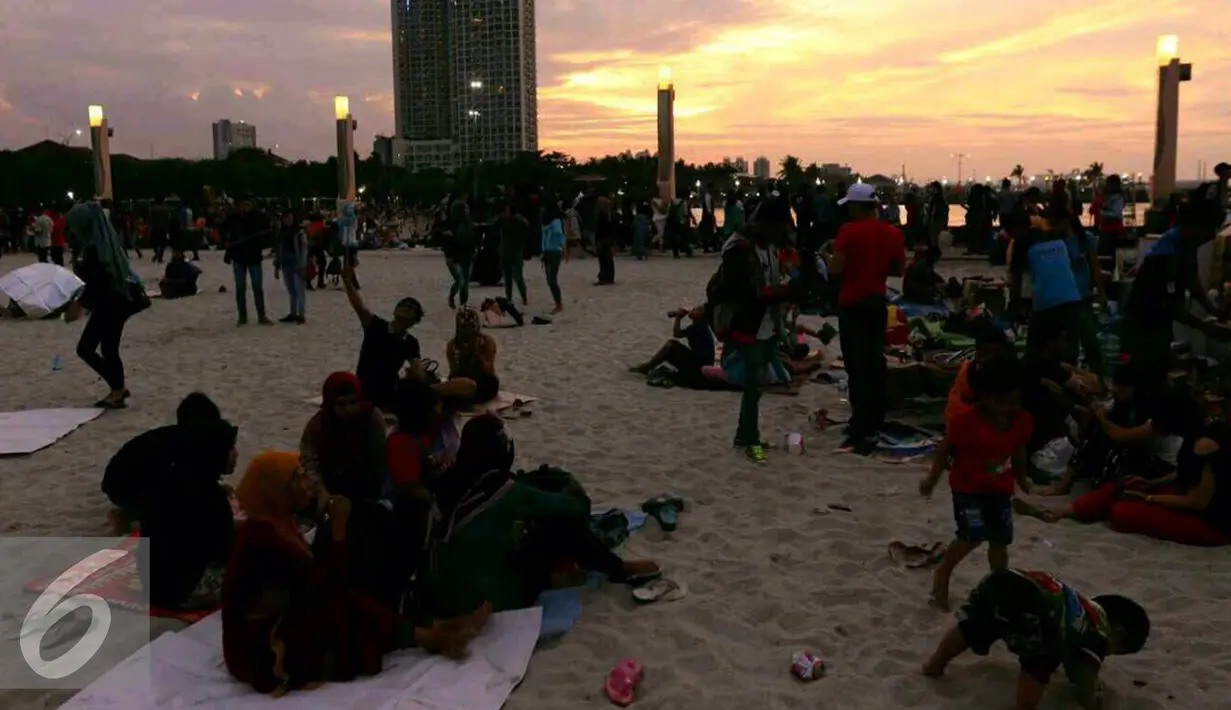 Pengunjung duduk disekitar pantai Ancol sambil menikmati matahari terbenam, Jakarta, Sabtu (31/12). Sebagian masyarakat merayakan pergantian tahun baru di pesisir Jakarta untuk menikmati matahari terbenam. (Liputan6.com/Angga Yuniar)
