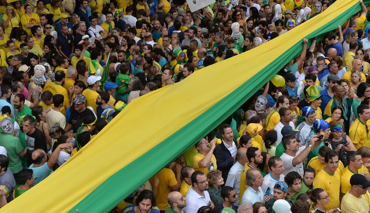 Massa membawa bendera raksasa saat unjuk rasa menuntut pengunduran diri Presiden Dilma Rousseff di Sao Paulo, Brasil, Minggu (13/3). Mereka menuduh Rousseff tidak mampu mengelola ekonomi dan terlibat dalam skandal korupsi besar. (NELSON Almeida/AFP)