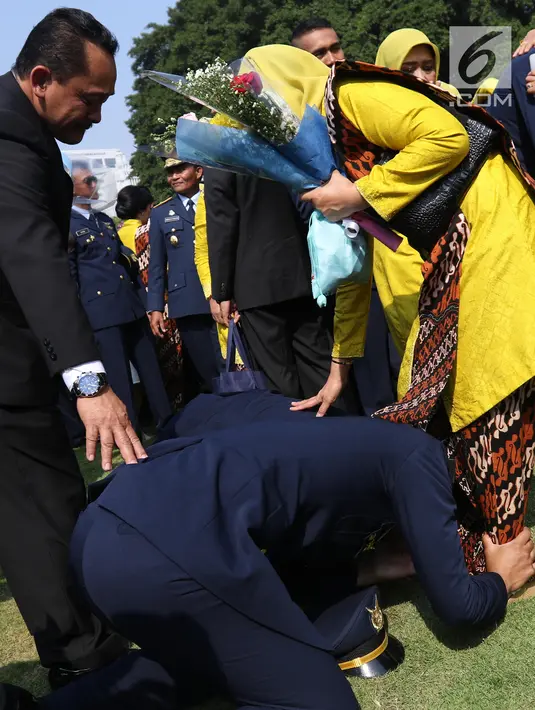 Perwira TNI-Polri mencium kaki orangtuanya usai dilantik Presiden Joko Widodo atau Jokowi di halaman Istana Merdeka, Jakarta Pusat, Selasa (16/7/2019). Jokowi melantik 259 perwira Akademi Militer, 117 Angkatan Laut, 99 Angkatan Udara, dan 306 Polri. (Liputan6.com/Angga Yuniar)