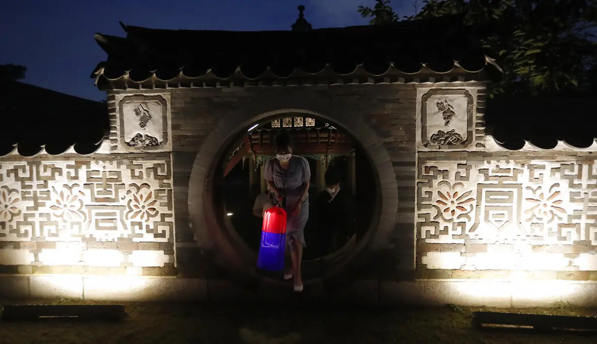 Seorang pengunjung memegang lentera tradisional Korea berjalan-jalan selama Tur Cahaya Bulan di Istana Changdeokgung di Seoul, Korea Selatan, Kamis, (13/8/2020). Istana dibuka kembali pada Kamis setelah ditutup selama dua bulan karena pandemi Covid-19. (AP Photo/Ahn Young-joon)