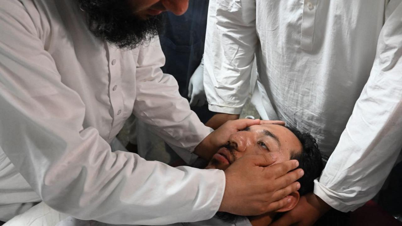 Seorang pria berusaha menyadarkan rekannya yang terluka saat mendapat perawatan di sebuah rumah sakit di Peshawa setelah menjadi korban ledakan bom bunuh diri pada 30 Juli 2023