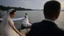 Pasangan berpose saat sesi pemotretan pernikahan di sebelah East Lake, Wuhan, Provinsi Hubei, China, 5 Agustus 2020. Pencabutan karantina 76 hari di Wuhan terkait COVID-19 pada April lalu membawa kehidupan dan lalu lintas kembali macet. (Hector Retamal/AFP)