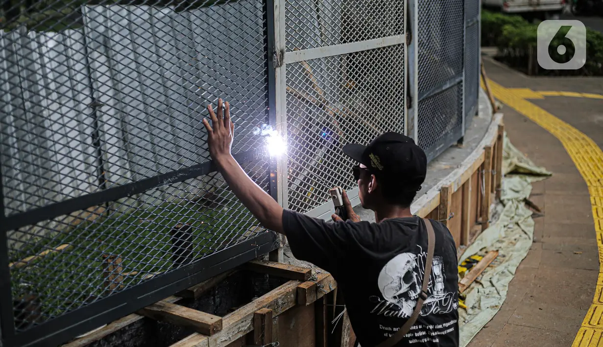 Pekerja melakukan pengelasan saat menyelesaikan pemasangan pagar yang mengelilingi area ruang terbuka hijau (RTH) Tebet Eco Park, Jakarta, Senin (12/12/2022). Pemprov DKI Jakarta melakukan pembatasan jumlah pengunjung taman dengan pembuatan sistem pendaftaran masuk pengunjung melalui JAKI sejak Juli 2022. (Liputan6.com/Faizal Fanani)