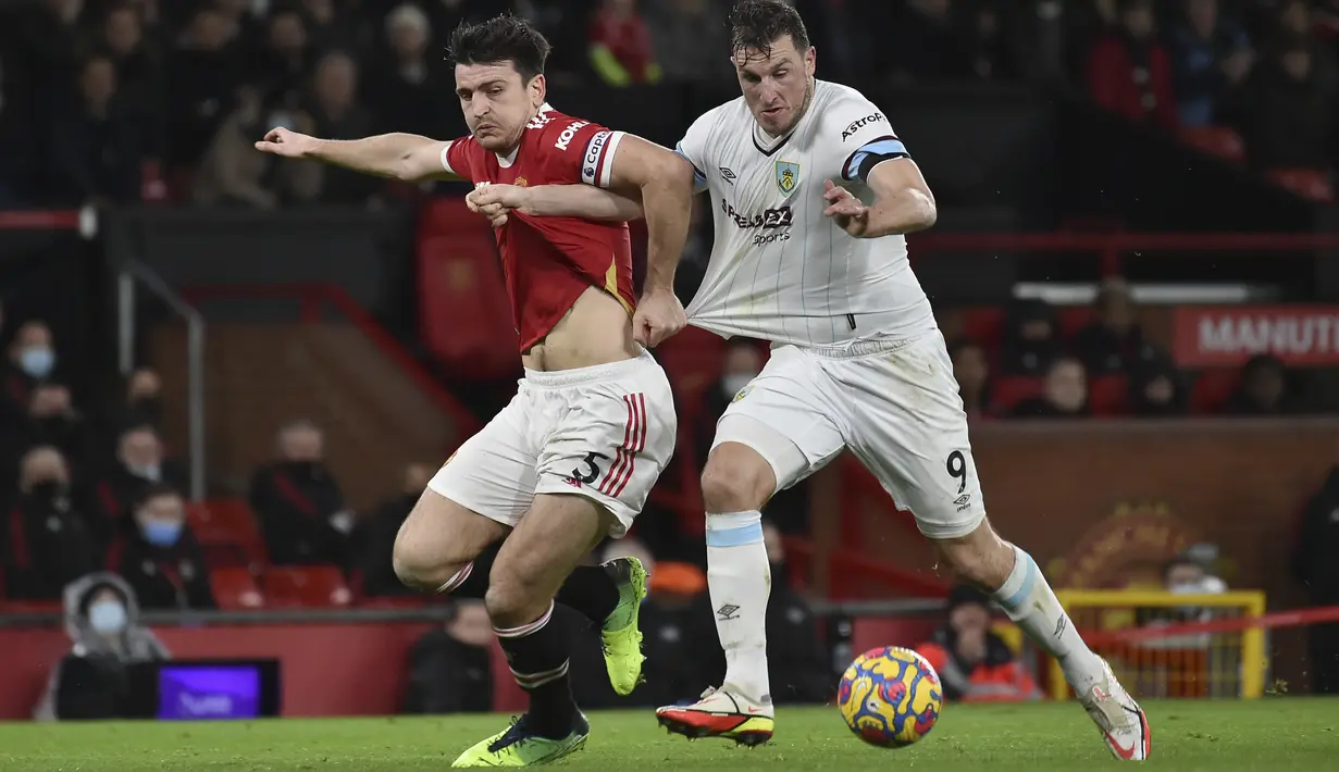 Bek Manchester United, Harry Maguire (kiri) berebut bola dengan pemain Burnley, Chris Wood selama pertandingan lanjutan Liga Inggris di di Old Trafford, Inggris, Jumat (31/12/2021). Man United menghuni urutan enam dengan nilai 31. (AP Photo/Rui Vieira)