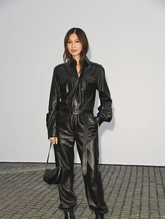 Gemma Chan tampil edgy dengan setelan jumpsuit kulit hitam bergaya militer lengkap dengan sabuk kulit, tas selempang hitam, dan ankle boots hitam. [dok. Burberry]