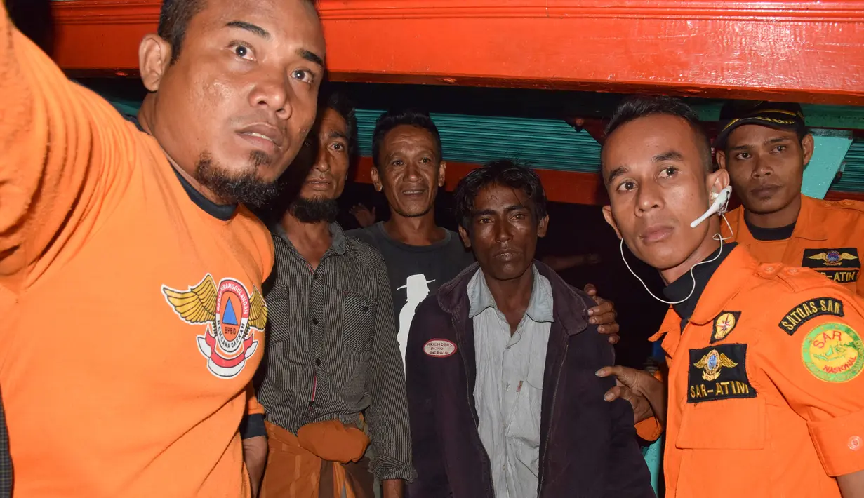 Petugas penyelamat mengevakuasi dua pria etnis Rohingya yang diselamatkan setelah terdampar di perairan Aceh, Kamis (5/4). Lima imigran Rohingya ditemukan dalam keadaan lemas terombang-ambing dengan menumpangi perahu kayu tanpa mesin. (ILYAS ISMAIL/AFP)