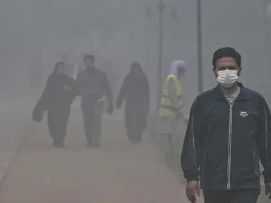 Orang-orang berjalan di sekitar taman di tengah kondisi kabut asap tebal di Lahore pada Kamis 7 November 2024. (Arif ALI/AFP)