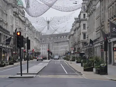 Suasana jalan ke arah Piccadilly Circus, di pusat kota London yang kosong pada Hari Natal, Sabtu (25/12/2021). Dari Bethlehem dan Frankfurt ke London dan Boston, gelombang virus corona varian omicron meredam Malam Natal untuk tahun kedua. (Jonathan Brady/PA via AP)