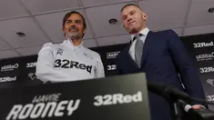 Mantan kapten Inggris, Wayne Rooney dan Manajer Derby County Phillip Cocu berjabat tangan usai konferensi pers di Stadion Pride Park, pinggiran kota Derby, Selasa (6/8/2019). Wayne Rooney diikat kontrak dengan Derby County selama 18 bulan yang akan efektif mulai Januari 2020. (Darren STAPLES / AFP)