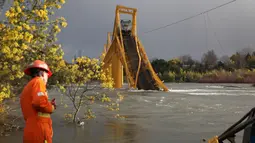 Petugas evakuasi melihat kereta barang yang anjlok ke dalam Sungai Tolten setelah jembatan tersebut runtuh di Desa Pitrufquen, sabelah selatan Chili. (18/08). (REUTERS/Cristobal)