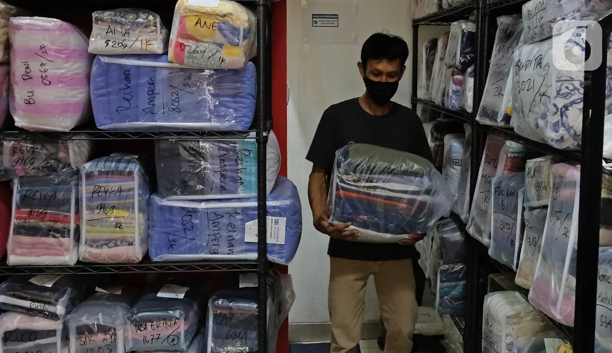 Pekerja membawa pakaian pelanggan di gerai jasa layanan laundry, kawasan Kemang, Jakarta, Rabu (25/11/2020). Banyaknya pekerja yang sudah kembali bekerja di kantor dan memasuki musim hujan diprediksi akan meningkatkan omset jasa laundry yang cukup signifikan. (Liputan6.com/Herman Zakharia)