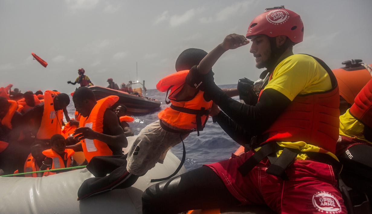 Petugas LSM Spanyol menyelamatkan anak imigran dari Afrika sub-Sahara di tengah Laut Mediterania, Selasa (25/7). Juru bicara penjaga pantai Italia mengatakan sekitar 260 migran telah diselamatkan dari perahu yang berbeda pada hari itu. (AP/Santi Palacios)