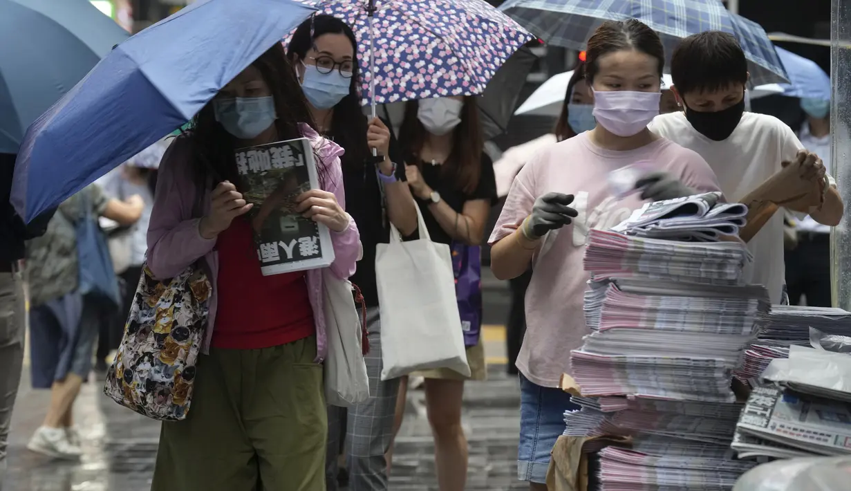 Orang-orang membeli edisi terakhir Apple Daily di stan surat kabar di jalan pusat kota di Hong Kong, Kamis (24/6/2021). Sebelumnya, kantor surat kabar itu igerebek polisi dan pemilik beserta lima eksekutifnya ditangkap di bawah undang-undang keamanan nasional yang baru. (AP Photo/Vincent Yu)