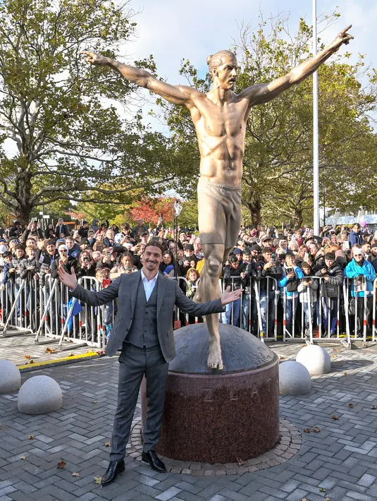 Bintang sepak bola Swedia, Zlatan Ibrahimovic berpose dengan patung yang menyerupainya dekat Stadion Malmo, Malmo, Swedia, Selasa (8/10/2019). Patung perunggu tersebut menjadi simbol kehebatan perjalanan karier Ibrahimovic di dunia sepak bola. (Johan NILSSON/TT News Agency/AFP)