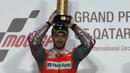 Pembalap Ducati Andrea Dovizioso berpose diatas podium sambil memegang pialanya usai memenangkan balapan di MotoGP Qatar 2018 di Sirkuit Internasional Losail (18/3). (AFP Photo/Karim Jaafar)