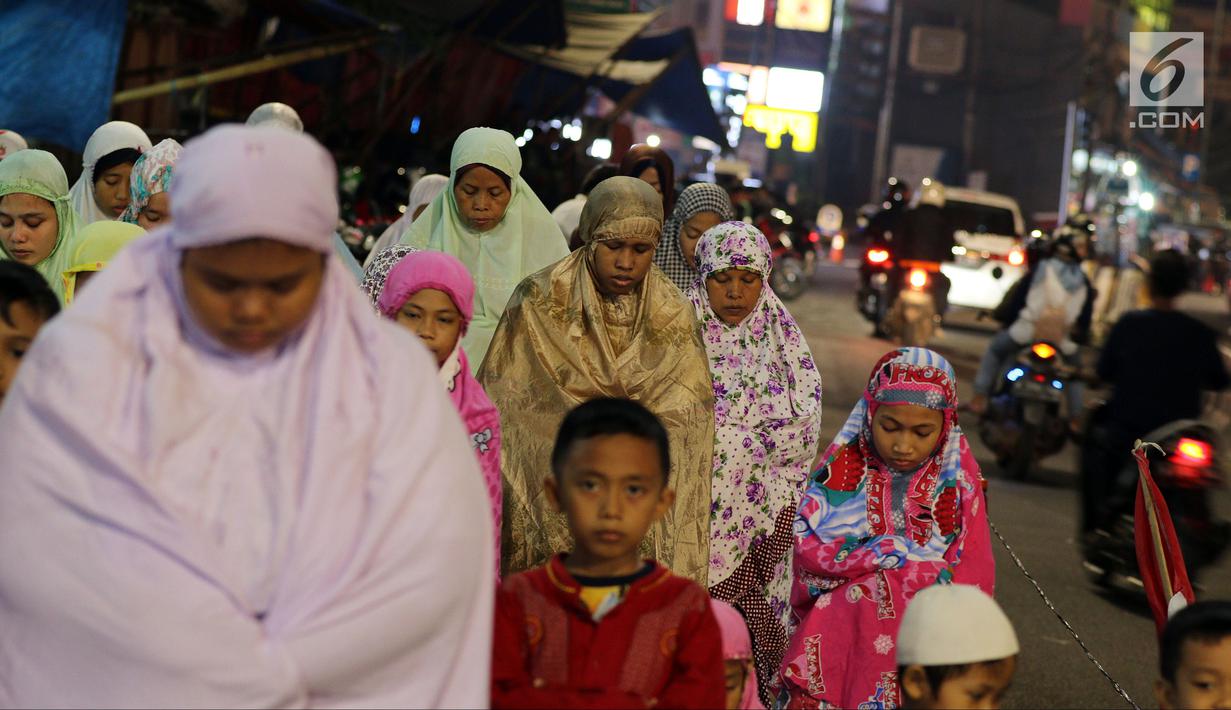 Jemaah wanita melaksanakan salat tarawih hingga ke badan jalan akibat melubernya Musala Miftahul Jannah di Kawasan Pasar Gembrong, Jakarta, Kamis (17/5). (Liputan6.com/JohanTallo)