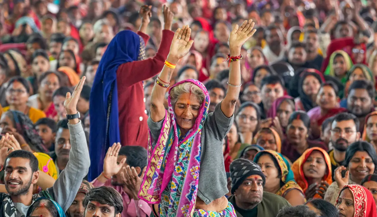 Umat Hindu menari saat mereka mendengarkan seorang pemimpin agama pada Festival Magh Mela di Sangam, pertemuan Sungai Gangga - Sungai Yamuna, Prayagraj, Uttar Pradesh, India, 31 Januari 2023. Ratusan ribu peziarah Hindu diperkirakan akan berenang dalam pertemuan tersebut, berharap bisa menghapus dosa selama festival sebulan penuh. (AP Photo/Rajesh Kumar Singh)