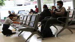 Pekerja membersihkan bangku ruang tunggu keberangkatan Stasiun Pasar Senen, Jakarta, Jumat (27/3/2020). PT Kereta Api Indonesia (Persero) membatalkan sejumlah jadwal perjalanan menyusul meluasnya penyebaran virus corona, pembatalan itu dilakukan mulai 26 Maret 2020. (Liputan6.com/Helmi Fithriansyah)