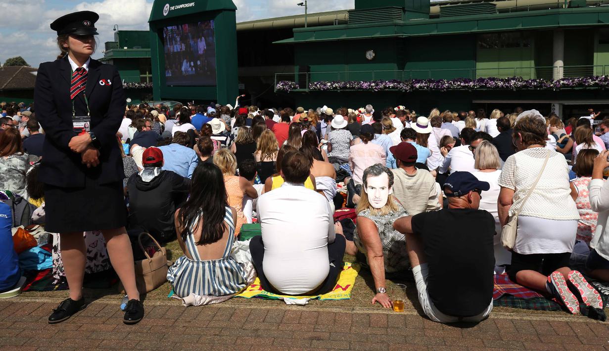 Petugas berjaga dekat ribuan penonton yang menyaksikan laga Andy Murray melawan Milos Raonic pada final tunggal putra  Wimbledon Championships 2016 di The All England Lawn Tennis Club,  Wimbledon, London, (10/7/2016).  (AFP/Justin Tallis)