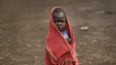 Seorang anak pengungsi muda Sudan Selatan berlindung dari rintik hujan di pemukiman pengungsi Bidi Bidi, Uganda, Selasa (6/6). Bidi Bidi adalah pemukiman pengungsi terbesar di dunia yang menampung pengungsi Sudan Selatan. (AP Photo / Ben Curtis)