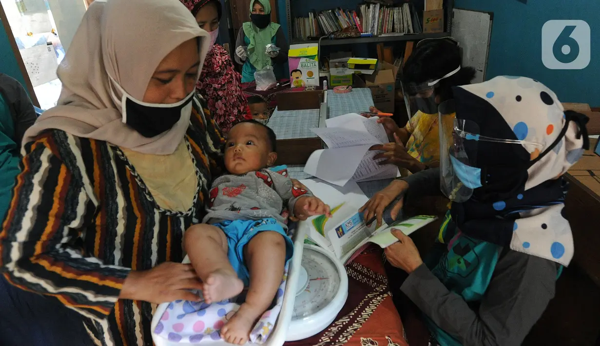 Petugas Posyandu menimbang badan balita sebelum pemberian vitamin A di Pos Ronda Kampung Kebon Jukut RW 10, Kelurahan Babakan Pasar, Kota Bogor, Kamis (6/8/2020). Kegiatan Posyandu untuk pertama kalinya selama pandemi corona ini bertepatan dengan pemberian vitamin A. (merdeka.com/Arie Basuki)