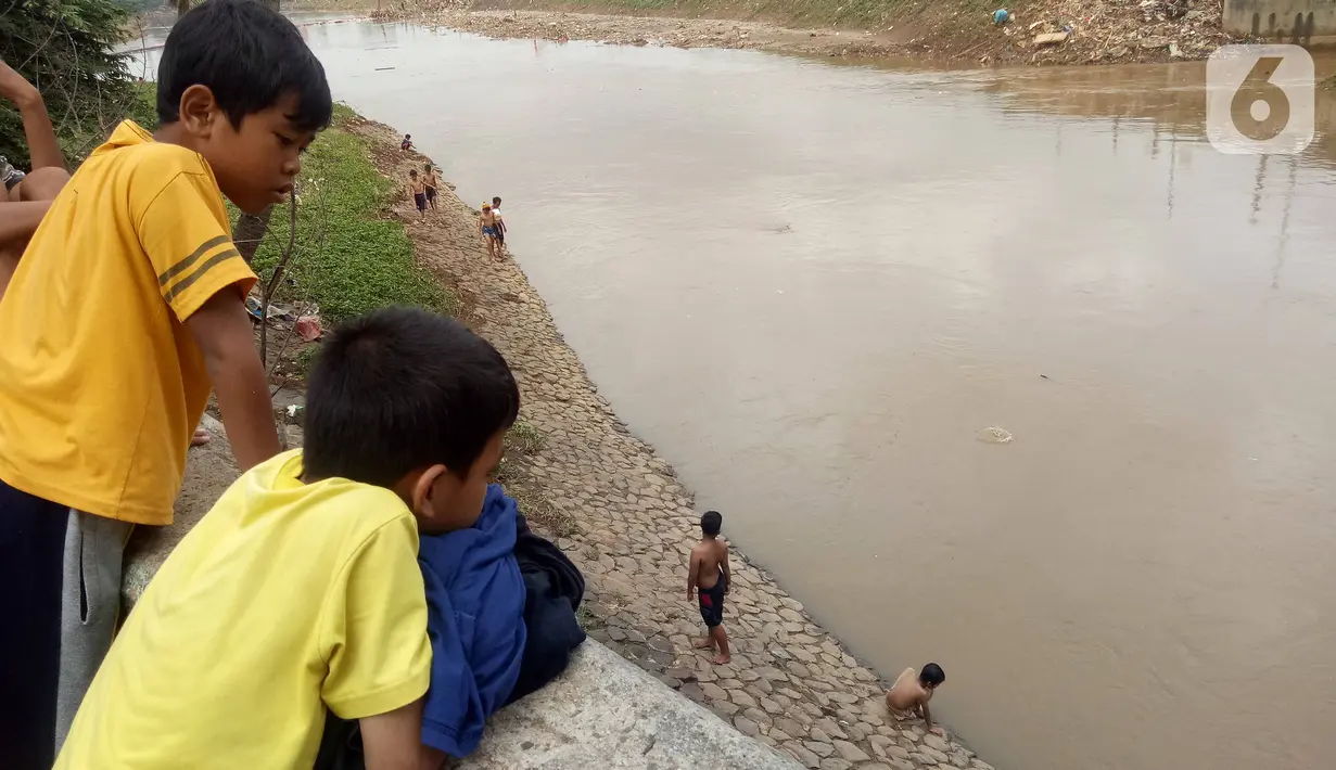 Anak-anak melihar teman-temannya  bermain di Bantaran sungai Kanal Banjir Barat, Tanah Abang, Jakarta, Sabtu (4/1/2020). Minimnya pengawasan  membuat anak-anak kerap bermain di tempat berbahaya yang berpotensi mengancam keselamatan mereka. (Liputan6.com/Angga Yuniar)