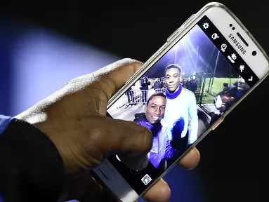 Fans menunjukan foto selfie bersama penyerang MU dan juga timnas Prancis, Anthony Martial usai menonton latihan skuat Les Blues jelang laga persahabatan melawan Jerman di Yvelines, Prancis, Selasa (10/11/2015). (AFP Photo/Franck Fife)