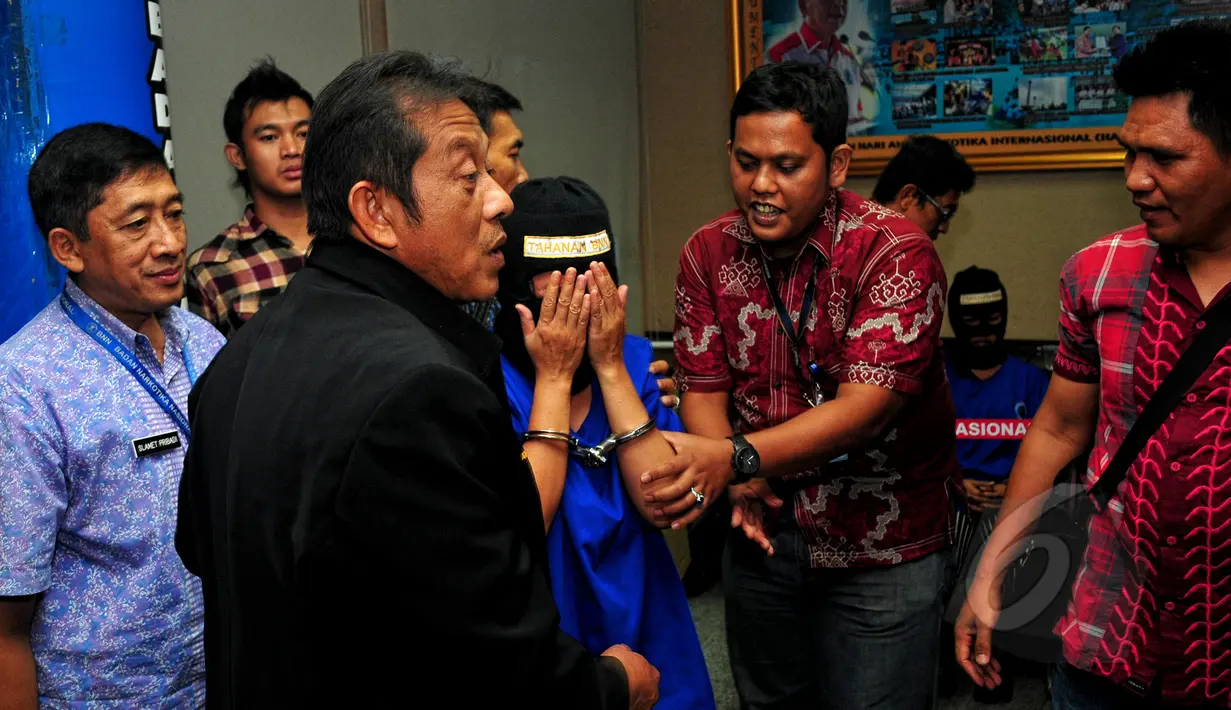 Salah satu kurir sabu, SA, terus menangis sambil menutup mukanya saat akan dibawa petugas menuju tahanan di Gedung BNN, Jakarta, Selasa (19/5). SA dan AN ditangkap aparat BNN dengan barang bukti 12,29 kg sabu. (Liputan6.com/Yoppy Renato)