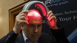 Seorang repoter televisi BBC mencoba alat bernama HairMax Laserband selama acara pembukaan Consumer Electronics Show di Las Vegas. (4/1). Alat ini jika dipakai mampu mengobati kerontokan rambut. (REUTERS / Rick Wilking)