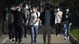 Penumpang yang mengenakan masker berjalan menuju kawasan pusat bisnis dari stasiun kereta bawah tanah yang belum ditutup di Beijing, Kamis (5/5/2022). Ibu kota China Beijing pada Kamis (5/5) mulai melonggarkan aturan karantina untuk kedatangan dari luar negeri. (AP Photo/Mark Schiefelbein)