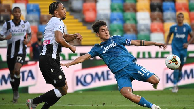Penyerang Juventus, Paulo Dybala menendang bola dari kawalan bek Udinese, William Troost-Ekong pada pertandingan lanjutan Liga Serie A Italia di Stadion Dacia Arena di Udine (23/7/2020). Udinese menang 2-1 atas Juventus. (AFP Photo/Marco Bertorello)