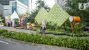 <p>Sejumlah warga berjalan melewati dekorasi bertemakan Idul Fitri di kawasan Bundaran HI, Jakarta, Rabu (27/4/2022). Dekorasi berbentuk masjid, ketupat, dan bedug yang dihiasi oleh tanaman tersebut dalam rangka menyambut Idul Fitri 1443 Hijriah. (Liputan6.com/Faizal Fanani)</p>