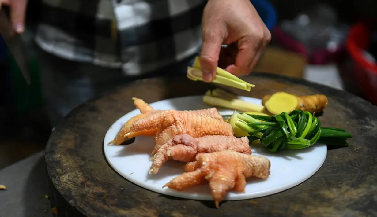 Seorang koki sedang menyiapkan ceker ayam Dong Tao di sebuah restoran di Hanoi, Vietnam, 15 Januari 2023. Awalnya daging dari ayam ini dikembangbiakkan secara eksklusif sehingga hanya bisa dikonsumsi oleh keluarga kerajaan saja. (Nhac NGUYEN/AFP)