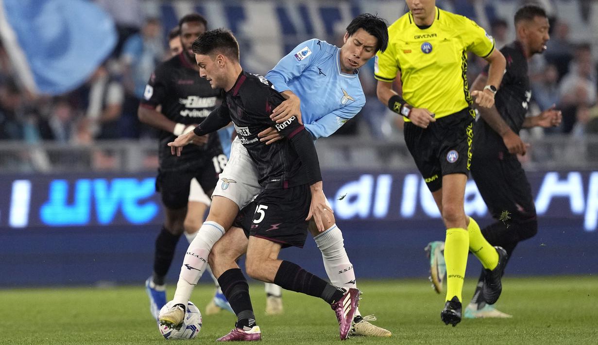 Pemain Lazio, Daichi Kamada (tengah) berebut bola dengan pemain Salernitana, Giulio Maggiore pada laga lanjutan Liga Italia 2023/2024 di Olympic Stadium, Roma, Italia, Sabtu (13/04/2024) dini hari WIB. (AP Photo/Andrew Medichini)