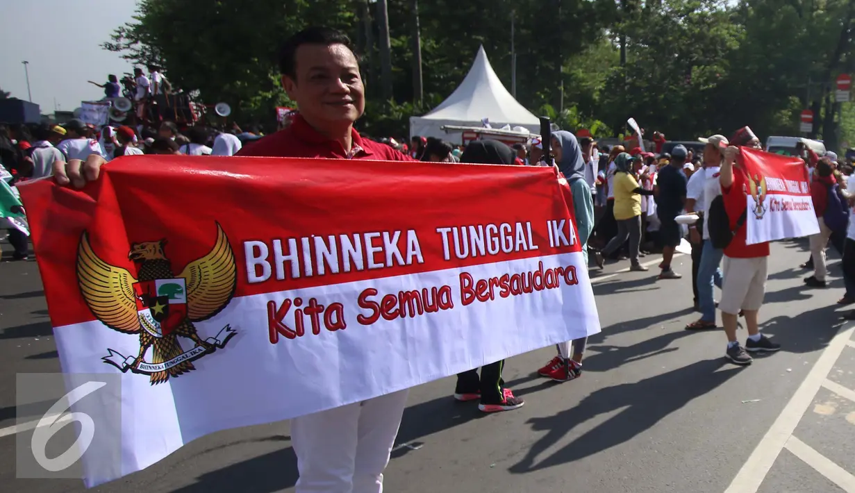Seorang peserta membentangkan spanduk saat mengikuti aksi Parade Bhineka Tunggal Ika di kawasan Patung Kuda di Jalan MH Thamrin, Jakarta Pusat, Sabtu (19/11). Parade tersebut juga bertujuan untuk mempererat persatuan bangsa. (Liputan6.com/Gempur M. Surya)