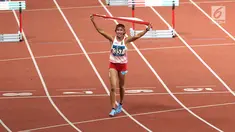 Pelari Indonesia, Nova Emilia membawa bendera merah putih usai finis di urutan kedua setelah pelari Korea Selatan Jung Hyelim pada final atletik nomor lari halang rintang 100 meter putri di Stadion Utama GBK, Jakarta (26/8). (Liputan6.com/Fery Pradolo)