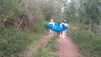 Potongan video yang menampilkan dua petugas dan seorang perempuan paruh baya menggotong jenazah Covid-19 yang terbungkus terpal beredar luas di media sosial. (Liputan6.com/ Dionisius)