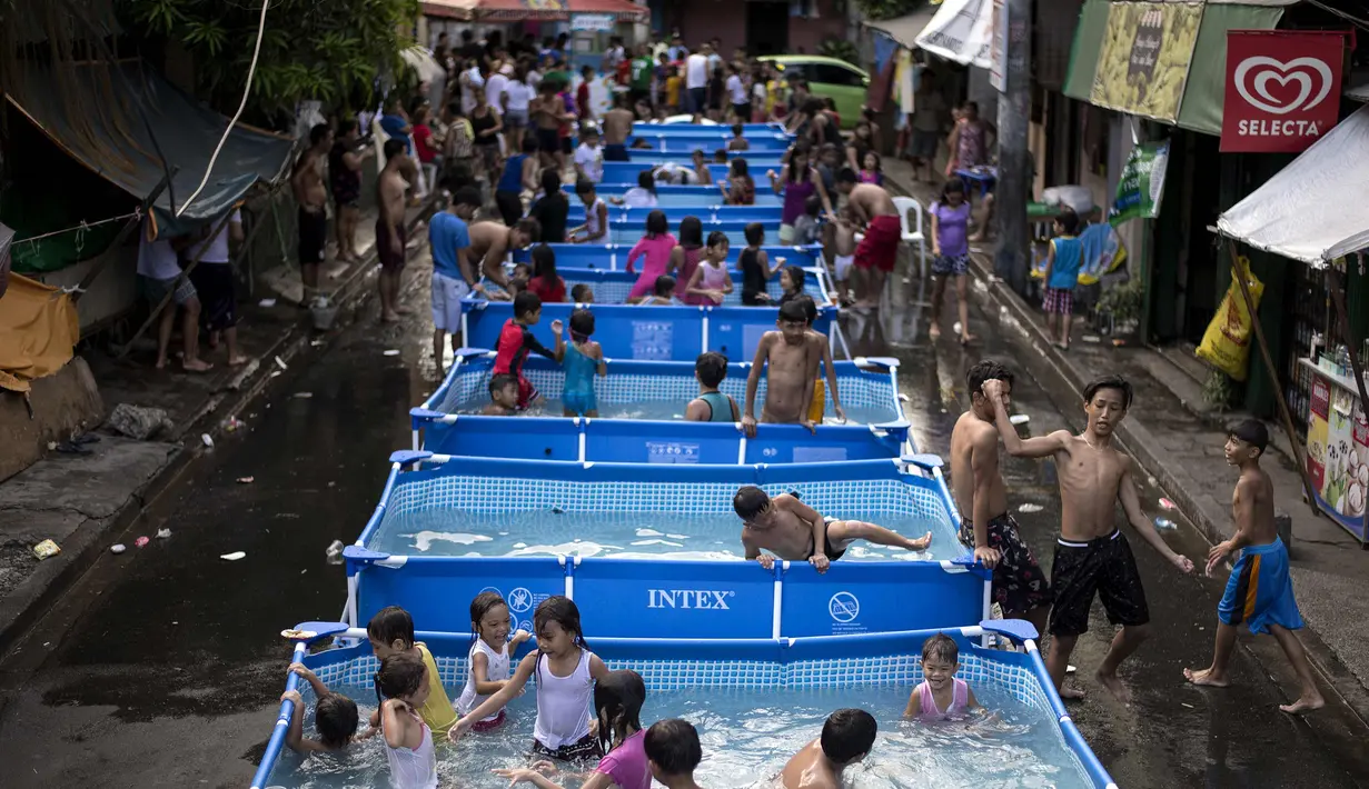 Anak-anak bermain di kolam portabel yang diberikan oleh pemerintah setempat untuk mendinginkan tubuh pada saat musim panas di Manila, Filipina (12/4). (AFP Photo/Noel Celis)