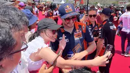 Sorang penggemar melakukan swafoto bersama pembalap Red Bull KTM, Jack Miller, dalam kegiatan MotoGP Hero Walk di Sirkuit Mandalika, Lombok , Minggu (15/10/2023). (Bola.com/Benediktus Gerendo Pradigdo)