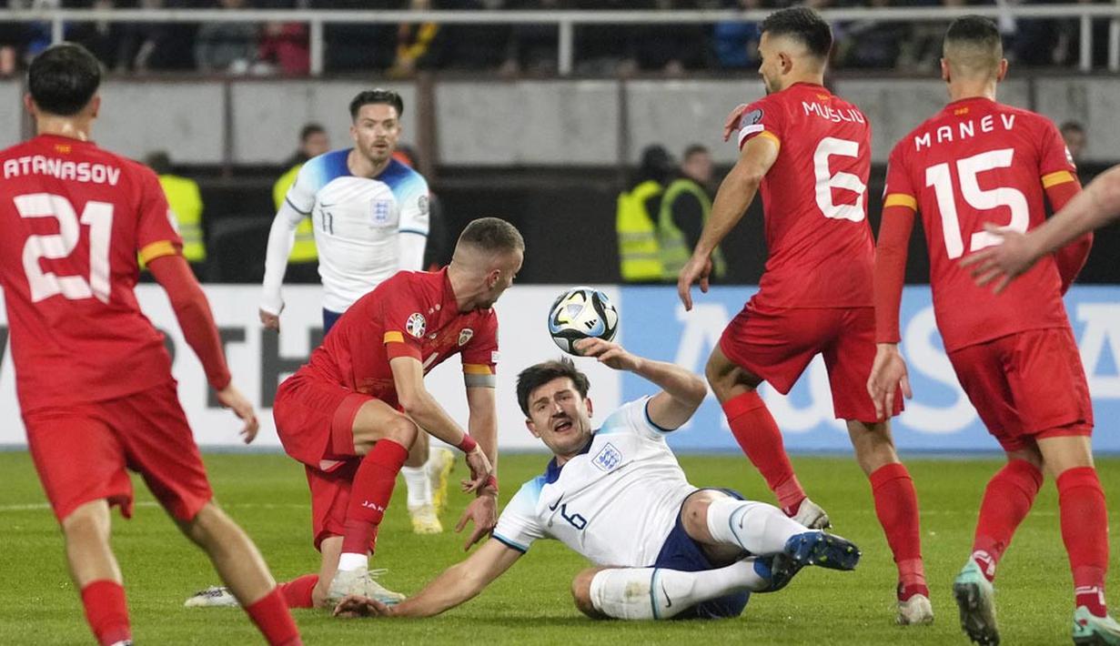 Pemain Inggris, Harry Maguire, terjatuh saat berebut bola dengan pemain Makedonia Utara dalam duel matchday 10 Kualifikasi Euro 2024 Grup C, Selasa (21/11/2023). (AP Photo/Darko Vojinovic)
