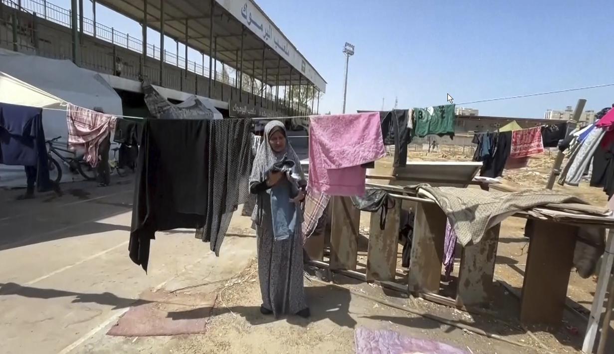 Gambar dari video ini memperlihatkan seorang perempuan menjemur pakaian di Stadion Olahraga Yarmouk, Kota Gaza, Jalur Gaza, Jumat 5 Juli 2024. (AP Photo)
