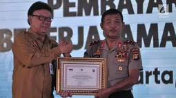 Mendagri Tjahjo Kumulo memberikan penghargaan kepada Kapolda Metro Jaya Irjen Pol Idham Aziz saat peresmian Samsat Digital dan Pembayaran Non Tunai di Jakarta, Senin (26/3). Sistem ini hasil kerja sama dengan Bank DKI. (Merdeka.com/Iqbal Nugroho)