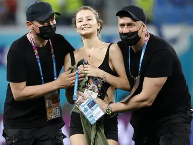 Petugas keamanan stadion menghentikan seorang penyusup lapangan wanita ketika pertandingan sepak bola Grup B UEFA EURO 2020 antara Finlandia melawan Belgia di Stadion Krestovsky, Saint Petersburg, Rusia, pada 21 Juni 2021. (AFP/Pool/Anatoly Maltsev)