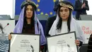 Nadia Murad basee Taha (kiri) dan Lamiya Aji Bashar, perempuan Yazidi yang diculik ISIS pada tahun 2014 dan dijadikan budak seks, menerima penghargaan Sakharov Prize 2016 di Parlemen Eropa di Strasbourg, Prancis, Selasa (13/12). (REUTERS/Vincent Kessler)
