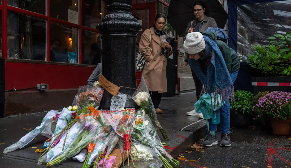 Para penggemar terlihat berkumpul di luar gedung, yang terletak di West Village, Manhattan, meninggalkan bunga-bunga di jalan dan mengambil foto-foto di tempat tersebut. (Adam GRAY / AFP)
