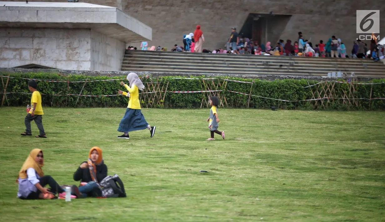 Pengunjung bermain di atas rumput saat mengunjungi Monumen Nasional (Monas) di Jakarta, Sabtu (22/12). Libur sekolah yang berbarengan dengan libur Natal dan Tahun Baru dimanfaatkan masyarakat untuk pergi berwisata ke Monas. (Liputan6.com/Faizal Fanani)