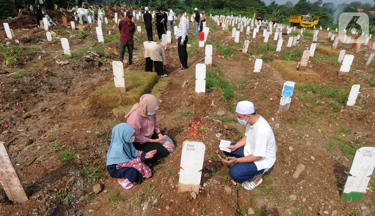 Warga berziarah dengan latar belakang pemakaman korban Covid-19 di TPU Srengseng Sawah 2, Jagakarsa, Jakarta, Senin (17/5/2021). Hari ini seluruh TPU di wilayah DKI dibuka untuk umum dengan menerapkan protokol kesehatan seperti pembatasan pengunjung dan waktu berziarah. (merdeka.com/Arie Basuki)